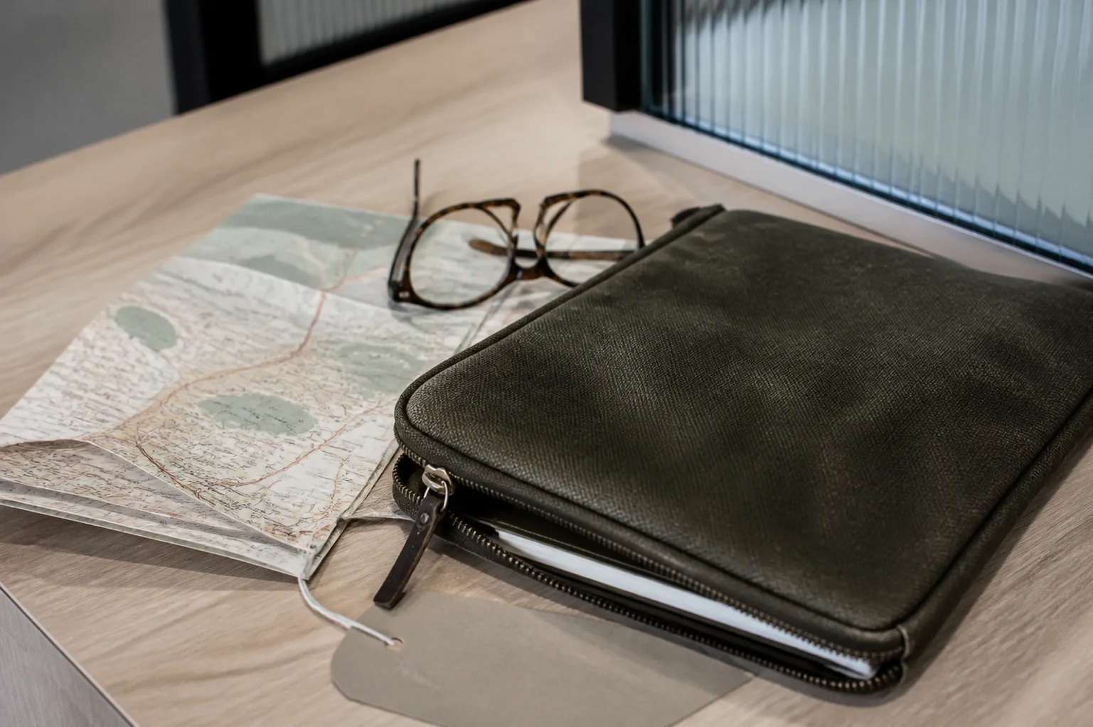 Editorial still life of travel-planning essentials on a pale oak table